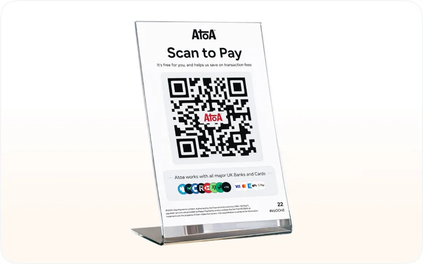 An Atoa Scan to Pay QR stand on a counter, showing the QR code and the UK bank and card logos it accepts