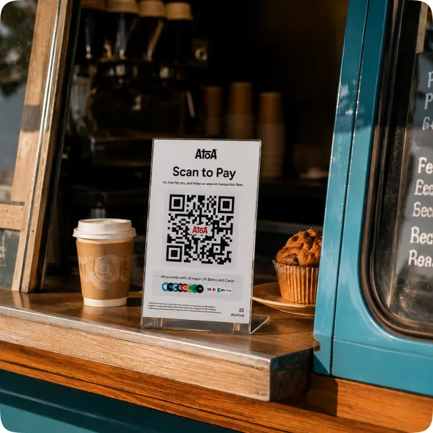 An Atoa Scan to Pay stand on the serving ledge of a coffee van beside a takeaway cup