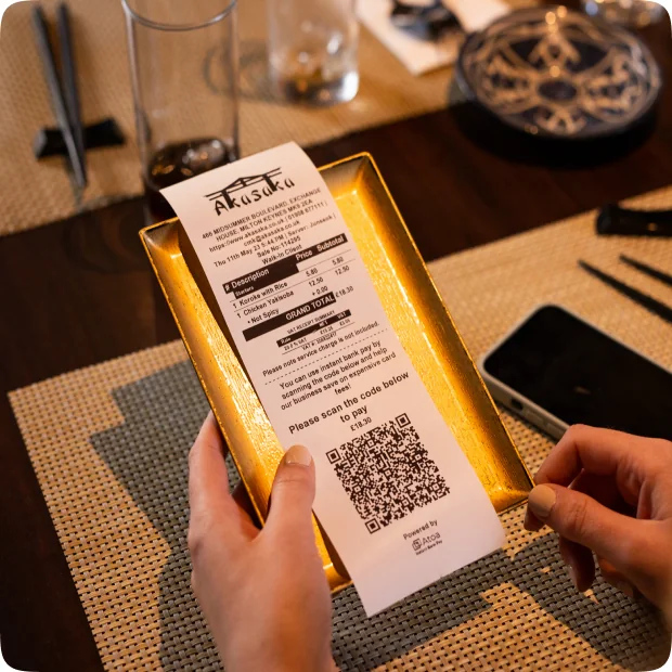 Guest at a restaurant table scanning an Atoa QR code shown on a handheld screen